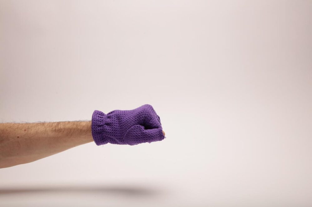 Hand in a purple glove making a fist